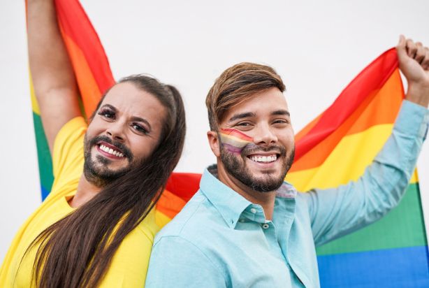 Duas pessoas carregando a bandeira LGBTQIAP+