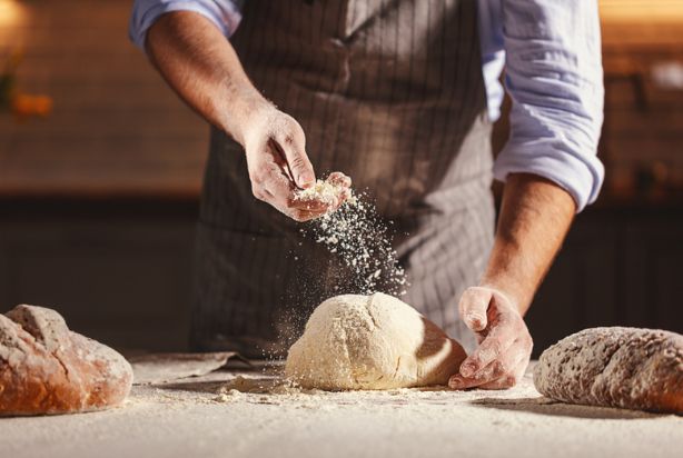 homem jogando farinha no pão 