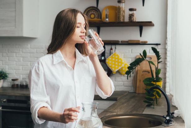 mulher bebendo água em casa
