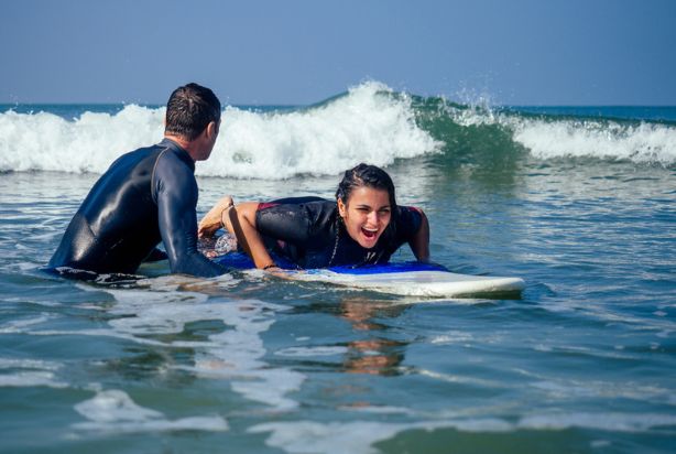 professor ensinando a aluna a surfar